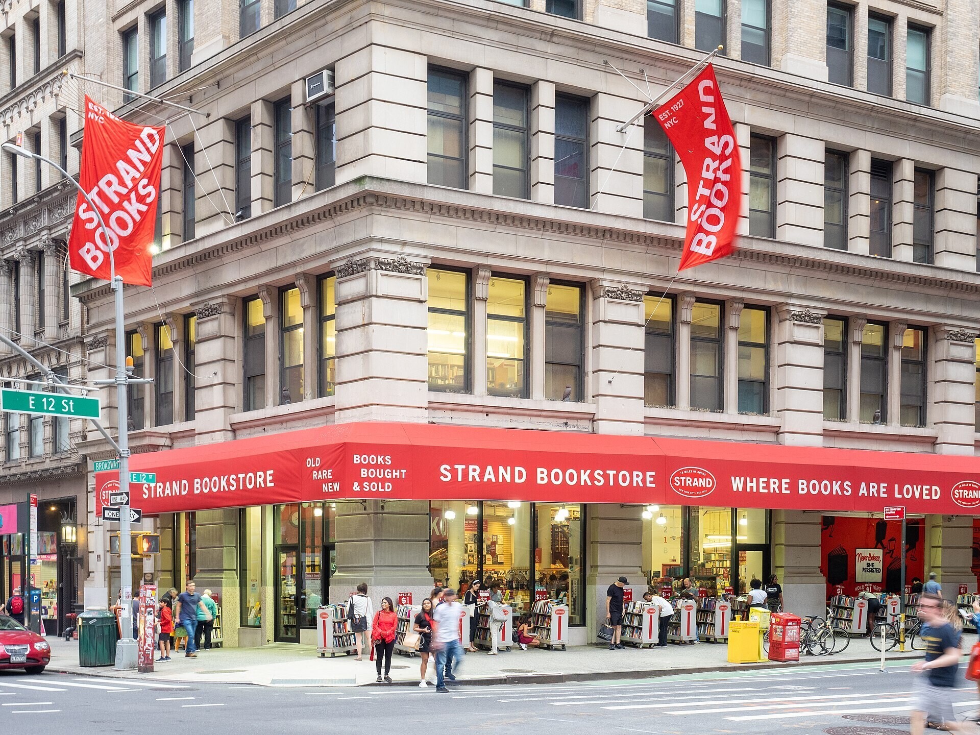 Exterior of Strand Bookstore with reddish  awnings and radical   browsing outdoor bookshelves