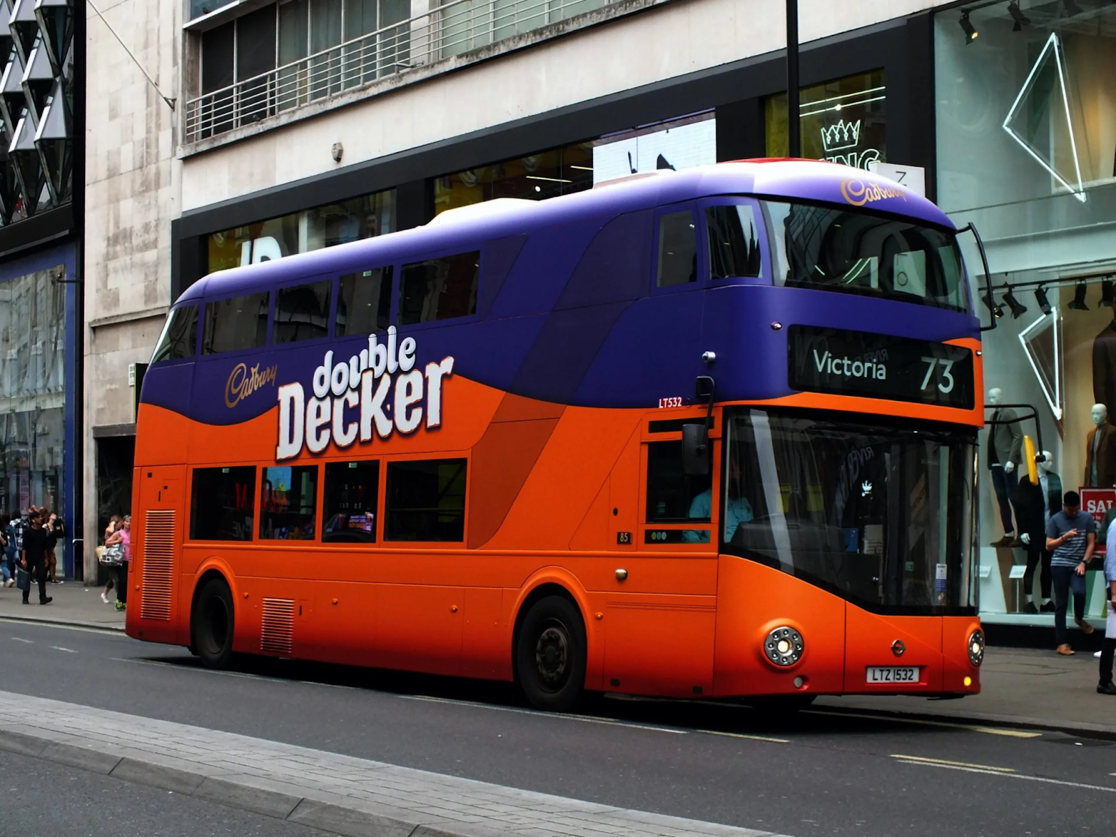 A London treble  decker autobus  showcasing a transit advertisement  for the marque  Cadbury UK, with the autobus  being wrapped arsenic  a treble  decker cocoa  bar.