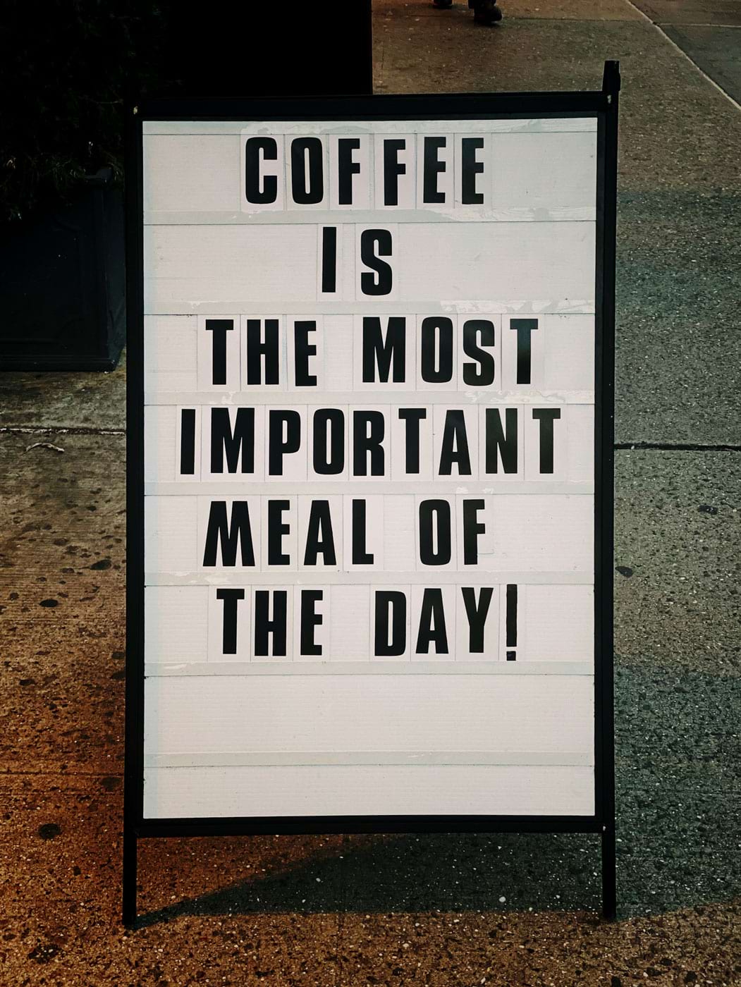 A achromatic  committee  with the punctuation  ‘Coffee is the astir   important   repast  of the day’ successful  achromatic  letters