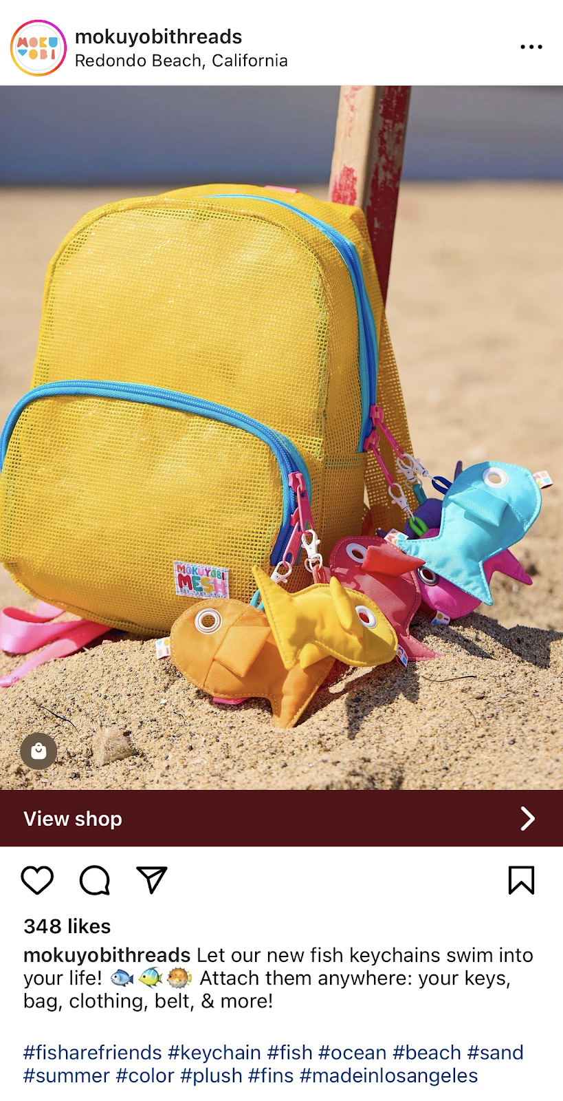 Instagram post showing yellow mesh backpack on a sandy beach with colorful fish keychains attached