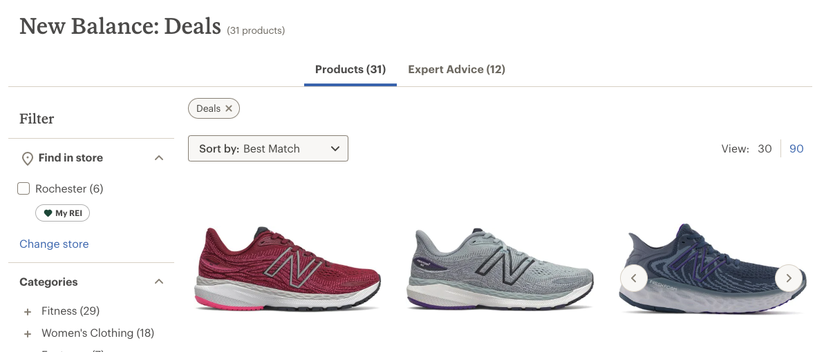 A screenshot of REI.com shows their current discounts on New Balance sneakers. There is an image of three New Balance sneakers, side-by-side—a red sneaker, a gray sneaker, and a mult-colored black and gray sneaker. 