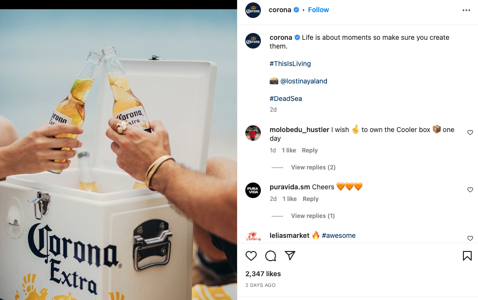 A screen capture of Corona’s Instagram feed shows an image of two people toasting Corona Extra beers over a Corona-branded cooler. The ocean is seen in the background.