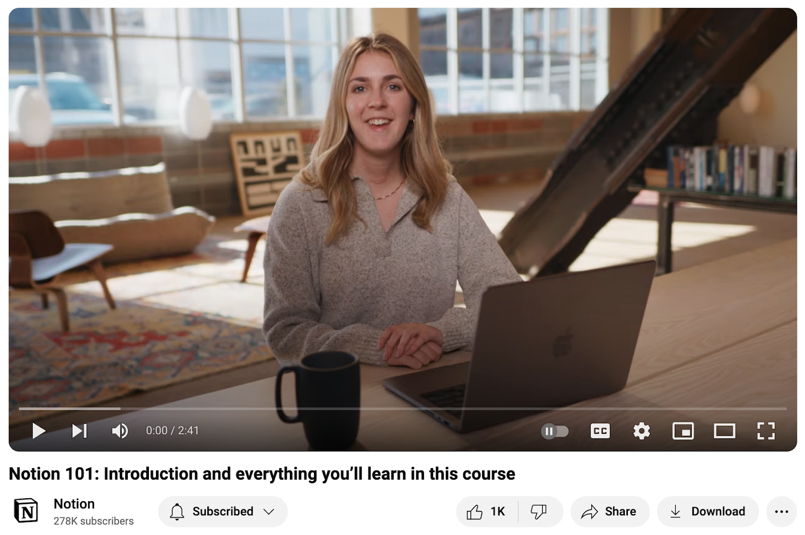 YouTube still frame from a Notion video course showing a person seated at a table with a laptop