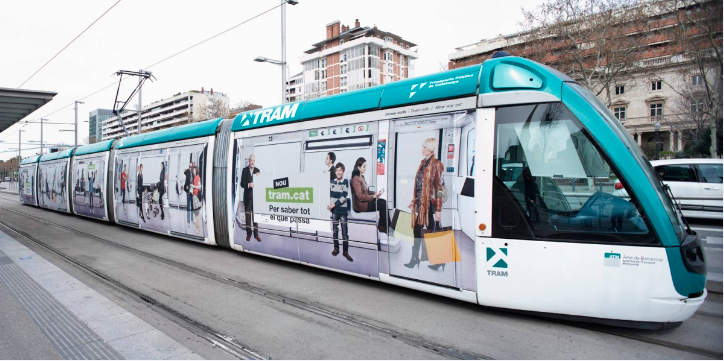 A tram showing ads being wrapped connected  the full  extracurricular  of the tram.