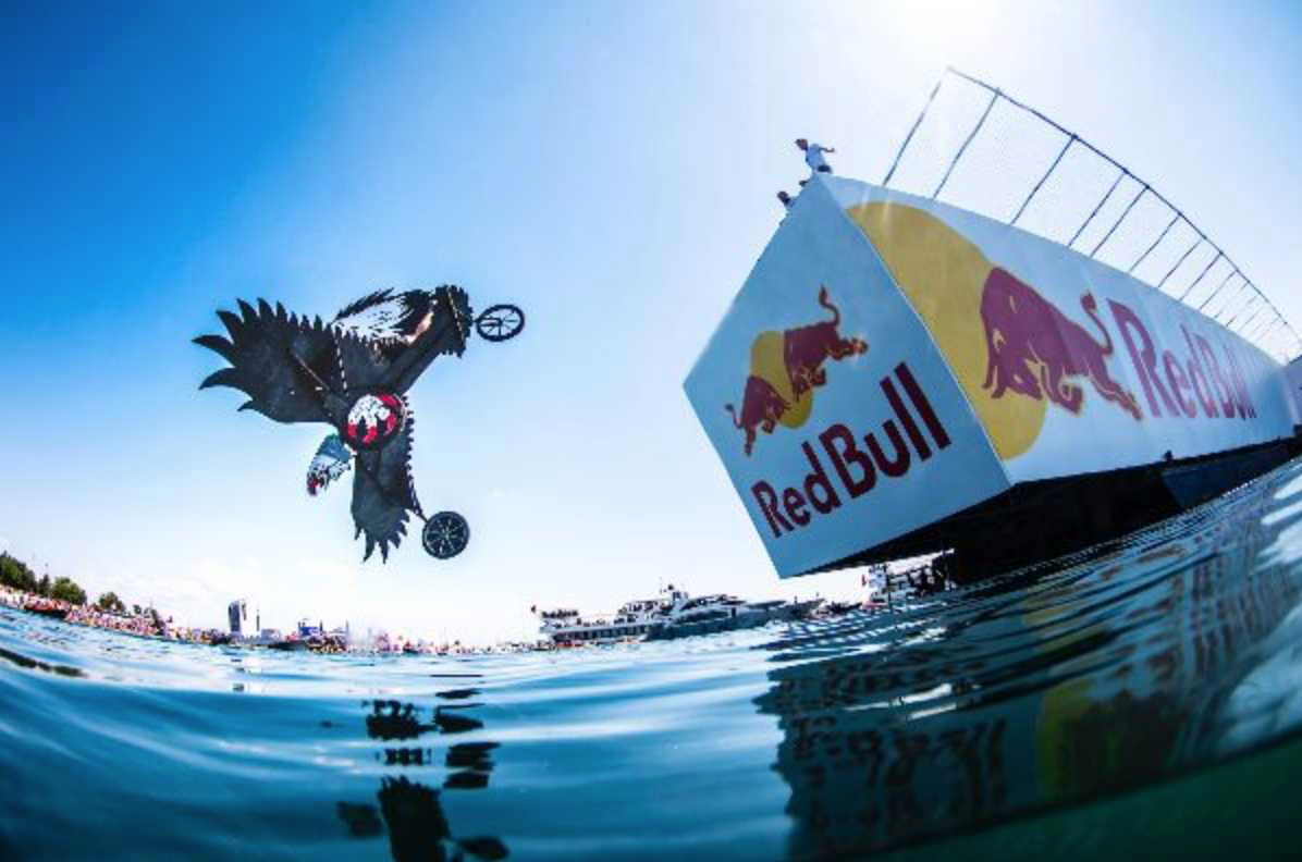 Red Bull extreme sport event showing a bike that just launched off a platform about to land into the water.